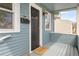 Inviting covered porch featuring classic blue siding, a dark door, and a 'Welcome' mat at 4933 Grove St, Denver, CO 80221