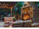 Cozy outdoor stone fireplace with comfortable seating beneath a pergola with string lights at 35 Brookhaven Pl, Littleton, CO 80123