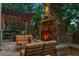 Outdoor stone fireplace with cozy seating area and a pergola illuminated by string lights at 35 Brookhaven Pl, Littleton, CO 80123