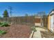Fenced backyard featuring a storage shed, mature trees, mulch beds, and access gate at 5703 Ammons St, Arvada, CO 80002