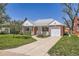 Traditional brick home with manicured lawn, mature trees, and a driveway leading to a garage at 5703 Ammons St, Arvada, CO 80002