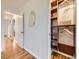 Hallway with wood floors, decorative mirror and view to closet with custom shelves at 5703 Ammons St, Arvada, CO 80002