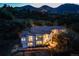 Aerial view of a two-story home with a tile roof and large windows nestled on a hillside with mountain views at dusk at 5799 Crestbrook Cir, Morrison, CO 80465