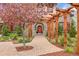 Inviting stone home featuring a beautiful flowering tree, lovely landscaping, and a welcoming covered walkway to the arched front door at 1423 E Fair Pl, Centennial, CO 80121