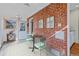 Charming sunroom with exposed brick, complemented by a table and two chairs at 1273 S Jackson St, Denver, CO 80210