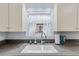 Well-lit kitchen sink with granite countertops, white cabinetry, and decorative window treatment at 1273 S Jackson St, Denver, CO 80210