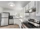 Bright kitchen features stainless steel appliances, white cabinets and grey backsplash at 1225 S Xavier St, Denver, CO 80219