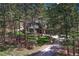 Exterior shot of the house partially obscured by tall trees with a glimpse of the driveway at 1410 Old Sequoia Ct, Franktown, CO 80116