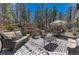 Inviting outdoor living space with cozy seating, dining area, and lush forest backdrop at 1410 Old Sequoia Ct, Franktown, CO 80116