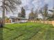 Large backyard with a lush lawn, a newly stained fence, and mature trees providing ample shade at 920 S Hudson St, Denver, CO 80246