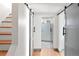 Bright hallway with wooden floors, stairs, and modern barn doors leading to the bathroom with glass enclosed shower at 720 S Clayton St, Denver, CO 80209