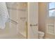 Modern bathroom shower with glass door and a built-in bench, alongside beige tile walls and golden hardware at 7649 Pineridge Ter, Castle Pines, CO 80108