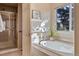 Luxurious bathroom with a soaking tub, glass shower, and a large window offering natural light and privacy at 7649 Pineridge Ter, Castle Pines, CO 80108