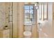 Bright bathroom featuring a marble tile shower with a bench, a toilet, and a window at 7649 Pineridge Ter, Castle Pines, CO 80108