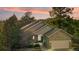 Charming home with a stone garage, well-manicured landscaping, and colorful sunset skies at 7649 Pineridge Ter, Castle Pines, CO 80108