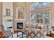 Elegant living room with a cozy fireplace, hardwood floors, and large windows, bringing the outdoors in at 7649 Pineridge Ter, Castle Pines, CO 80108