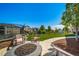 Spacious backyard with a firepit, Adirondack chairs, grass, and lush landscaping creating a great outdoor living area at 23879 E Narrowleaf Pl, Aurora, CO 80016