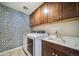 Well-organized laundry room with a modern washer and dryer, sink, and ample cabinet space at 23879 E Narrowleaf Pl, Aurora, CO 80016