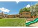 Expansive backyard with lush green lawn, mature trees, and a playset at 8272 Ammons Cir, Arvada, CO 80005
