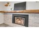 Close-up of a modern fireplace with a stone surround, wooden mantel, and a black art piece above at 8272 Ammons Cir, Arvada, CO 80005