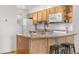Functional kitchen featuring wood cabinets, white appliances, and a breakfast bar for casual dining at 6330 E 13Th Ave, Denver, CO 80220