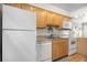 Bright kitchen with wood cabinets and white appliances, including a refrigerator, dishwasher, and oven at 6330 E 13Th Ave, Denver, CO 80220