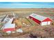 Aerial view of two red barns with white roofs and fenced enclosures in a rural setting at 48155 E 56Th Ave, Bennett, CO 80102