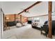 A spacious attic bedroom with exposed wooden beams, fireplace, and wood paneled accent wall at 48155 E 56Th Ave, Bennett, CO 80102