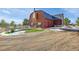 Barn-style home with a red garage door and wood exterior siding with a fenced in yard at 48155 E 56Th Ave, Bennett, CO 80102