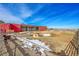 A red barn with goats grazing in a snowy paddock set against a backdrop of blue skies and sprawling fields at 48155 E 56Th Ave, Bennett, CO 80102