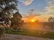 An exterior view shows yard and garden with trees and a sunset sky in the background at 48155 E 56Th Ave, Bennett, CO 80102