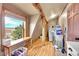 A well-lit laundry room with wooden beams, hardwood floors, and a front-loading washer and dryer at 48155 E 56Th Ave, Bennett, CO 80102