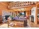 Cozy living room with a brick fireplace, exposed beams, and large windows showcasing the view at 48155 E 56Th Ave, Bennett, CO 80102