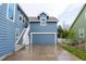 Rear exterior view features a two-car garage with a painted driveway and exterior staircase at 3186 Springmeadow Cir, Castle Rock, CO 80109