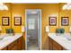 Bright bathroom with double sinks, warm colored walls, and a door leading to a separate toilet room at 2231 E 128Th Ave, Thornton, CO 80241