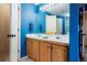 Bathroom featuring double vanity sinks, blue walls, and a large mirror with overhead lights at 4873 Eckert St, Castle Rock, CO 80104