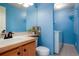 Bathroom with blue walls, a single vanity, toilet, tile floors, and a washing machine in the background at 4873 Eckert St, Castle Rock, CO 80104
