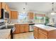 Bright kitchen featuring tile flooring, wood cabinets, stainless steel appliances, and a center island at 4873 Eckert St, Castle Rock, CO 80104