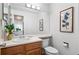 Bathroom with updated vanity, toilet, and décor; access to living room with wood ceiling at 13245 Shoshone St, Denver, CO 80234