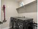 Modern laundry room featuring front loading black washer and dryer, floating shelf, and grey walls at 14096 Red Cosmos St, Parker, CO 80134