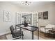 Home office with black desk, white walls, wood floors, and french doors leading to the combined kitchen and living space at 14096 Red Cosmos St, Parker, CO 80134