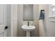 Simple powder room features a pedestal sink, black faucet, modern mirror and stylish hardware at 14096 Red Cosmos St, Parker, CO 80134