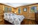 Bedroom with hardwood floors, wood paneling, a patterned comforter, and two windows at 5724 Highway 9, Breckenridge, CO 80424