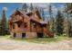 Charming log cabin with a stone foundation, wooden decks, and surrounded by tall pine trees at 5724 Highway 9, Breckenridge, CO 80424