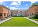 Full exterior view of a brick townhouse complex with a well-maintained central lawn area, showcasing its inviting community at 2858 Jasmine St, Denver, CO 80207