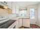 Cozy kitchen featuring white cabinetry, a window above the sink, and updated appliances, creating a classic look at 2858 Jasmine St, Denver, CO 80207