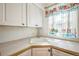 Bright kitchen featuring white cabinets, matching sink, and sunny window with floral curtains at 2858 Jasmine St, Denver, CO 80207