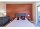 This bedroom features a rust colored accent wall, queen bed, dresser and sliding door at 1735 N Ogden St # 106, Denver, CO 80218