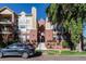 Attractive condominium building with red brick and tan facade, a car parked in front and greenery around the building at 1735 N Ogden St # 106, Denver, CO 80218