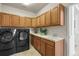 Spacious laundry room with wood cabinets, a utility sink, and a full-size washer and dryer at 6462 S Versailles Ct, Aurora, CO 80016